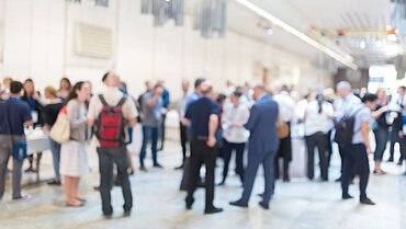 Viele Menschen unterhalten sich in unterschiedlichen Gruppen in einem großen Raum.