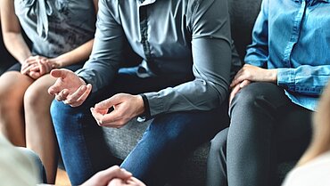 Mehrere Personen sitzen gestikulierend zusammen.