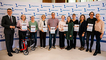 Eine Gruppe Personen steht in einer Reihe. Einige halten eine Urkunde in der Hand.